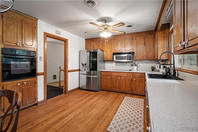 7708 Stonetree Dr, North Chesterfield, VA 23235 - kitchen with black appliances, a sink, brown cabinetry, light wood-style floors, and tasteful backsplash