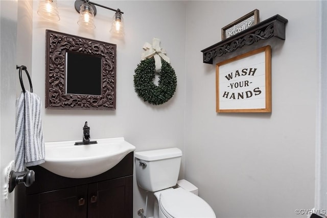 half bathroom featuring vanity and toilet