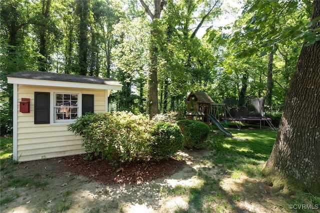 view of yard featuring a trampoline, a playground, and an outdoor structure