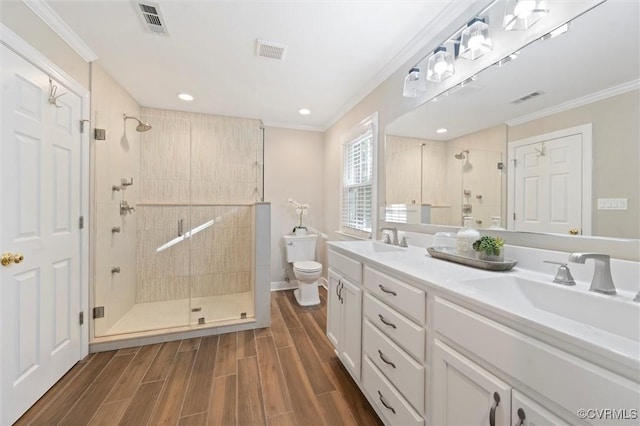 bathroom featuring toilet, a stall shower, ornamental molding, wood finish floors, and double vanity