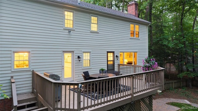 rear view of house featuring a wooden deck, a chimney, and outdoor dining area