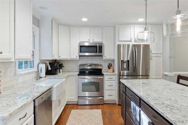 kitchen with stainless steel appliances, white cabinetry, wood finished floors, decorative backsplash, and light stone counters