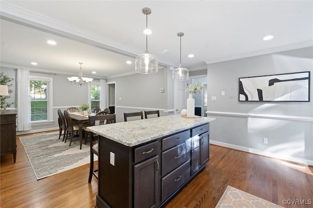 kitchen with a breakfast bar, a chandelier, crown molding, pendant lighting, and a center island