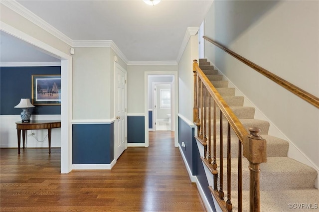 stairway with wood finished floors, crown molding, and baseboards