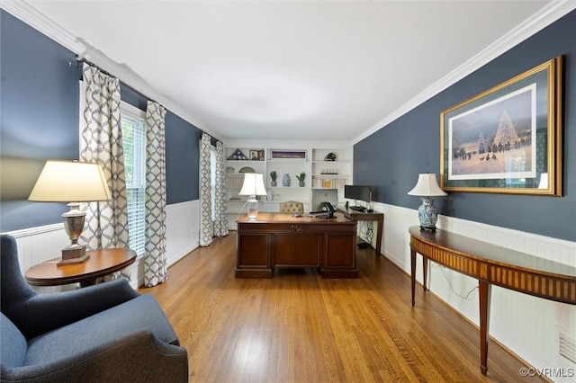 office area with wood finished floors, a wainscoted wall, crown molding, and built in features