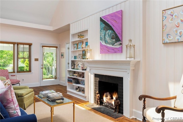 20 Winstead Dr, Irvington, VA 22480 - living room with vaulted ceiling, a warm lit fireplace, wood finished floors, built in shelves, and baseboards