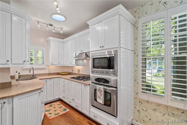 20 Winstead Dr, Irvington, VA 22480 - kitchen featuring appliances with stainless steel finishes, a sink, white cabinetry, under cabinet range hood, and wallpapered walls