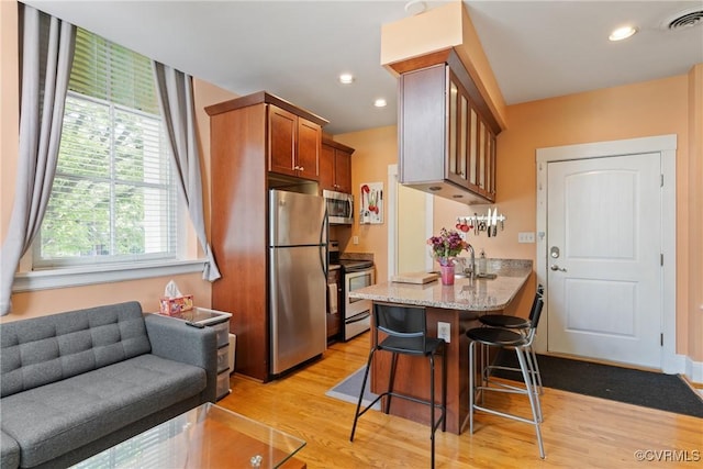 9 E Clay St Unit U2, Richmond, VA 23219 - kitchen with appliances with stainless steel finishes, light wood-style floors, a kitchen breakfast bar, light stone counters, and recessed lighting