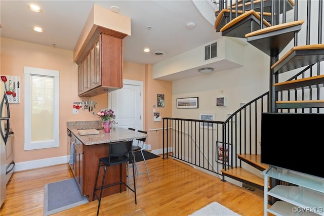 9 E Clay St Unit U2, Richmond, VA 23219 - kitchen featuring baseboards, light wood finished floors, brown cabinets, light stone counters, and recessed lighting