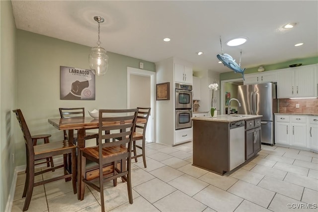 1825 Rock Point Dr, Powhatan, VA 23139 - kitchen with stainless steel appliances, white cabinets, backsplash, pendant lighting, and an island with sink