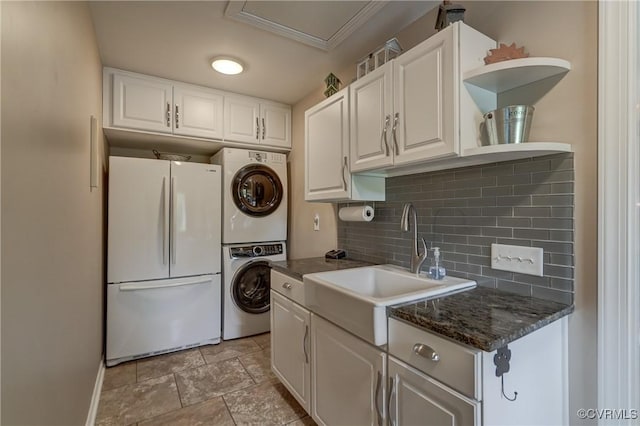 1825 Rock Point Dr, Powhatan, VA 23139 - kitchen featuring freestanding refrigerator, stacked washer and clothes dryer, a sink, decorative backsplash, and white cabinets