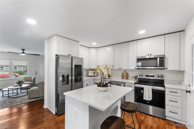 5314 Marian St, Richmond, VA 23226 - kitchen featuring appliances with stainless steel finishes, a breakfast bar, dark wood finished floors, white cabinets, and a center island
