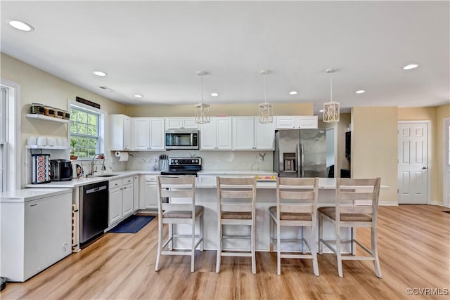 8118 Mimosa Hill Ln, Mechanicsville, VA 23116 - kitchen featuring appliances with stainless steel finishes, light wood-type flooring, white cabinetry, a center island, and light countertops