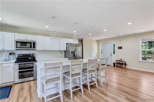 8118 Mimosa Hill Ln, Mechanicsville, VA 23116 - kitchen with appliances with stainless steel finishes, light wood-type flooring, white cabinetry, a kitchen island, and recessed lighting