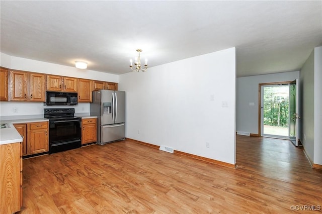 166 Marsha Ln, King William, VA 23086 - kitchen with black appliances, a chandelier, light countertops, light wood-style flooring, and baseboards