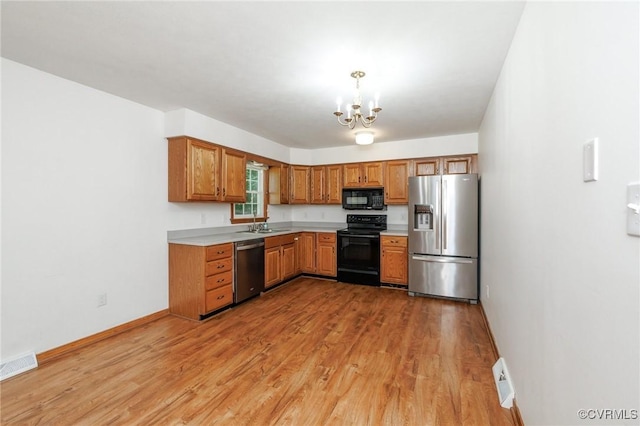 166 Marsha Ln, King William, VA 23086 - kitchen with black appliances, a chandelier, light countertops, light wood-type flooring, and baseboards