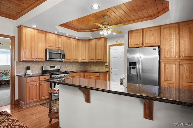 10003 Four Iron Ct, Fredericksburg, VA 22408 - kitchen featuring stainless steel appliances, wooden ceiling, light wood finished floors, a tray ceiling, and ornamental molding