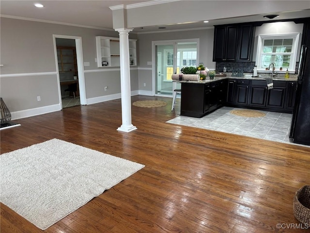 23766 Kings Hwy, Warsaw, VA 22572 - kitchen with decorative columns, ornamental molding, dark cabinetry, light wood-style floors, and a breakfast bar area