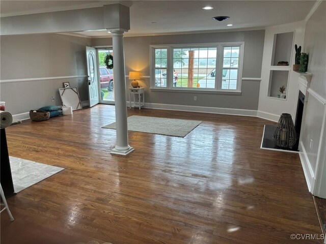 23766 Kings Hwy, Warsaw, VA 22572 - unfurnished living room featuring decorative columns, crown molding, built in shelves, wood finished floors, and baseboards