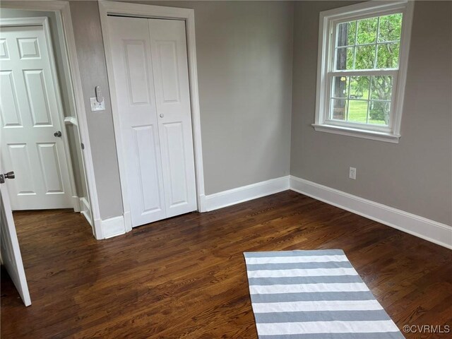 23766 Kings Hwy, Warsaw, VA 22572 - unfurnished bedroom featuring baseboards, a closet, and dark wood-style floors