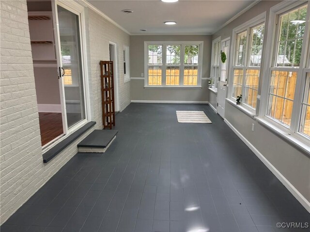 23766 Kings Hwy, Warsaw, VA 22572 - unfurnished sunroom with brick wall, baseboards, and crown molding