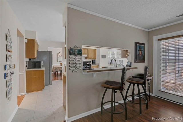 802 Westgate Ct, Newport News, VA 23602 - kitchen with a kitchen breakfast bar, black microwave, baseboards, a peninsula, and freestanding refrigerator