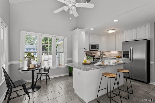 6730 Bryanbell Dr, North Chesterfield, VA 23234 - kitchen featuring stainless steel appliances, white cabinetry, a ceiling fan, backsplash, and high vaulted ceiling