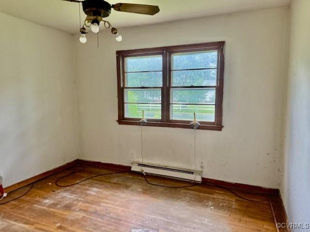 25468 Woodland Park Cir, Courtland, VA 23837 - unfurnished room featuring a baseboard heating unit, wood finished floors, baseboards, and a ceiling fan