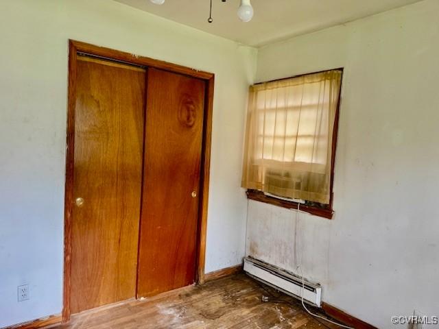 25468 Woodland Park Cir, Courtland, VA 23837 - unfurnished bedroom featuring a baseboard heating unit, wood finished floors, baseboards, and a closet
