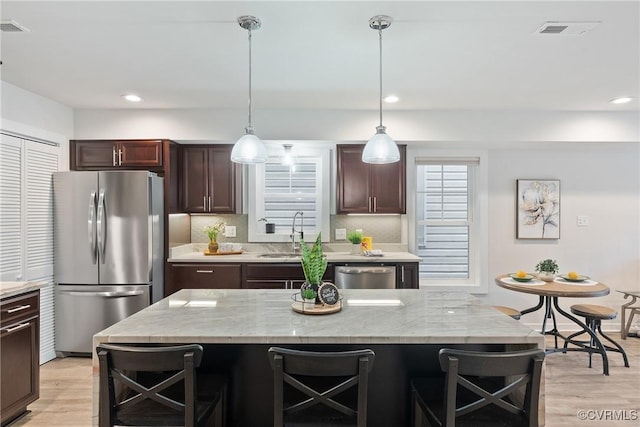1117 N 31st St, Richmond, VA 23223 - kitchen with appliances with stainless steel finishes, light wood-style floors, a breakfast bar, dark brown cabinetry, and recessed lighting