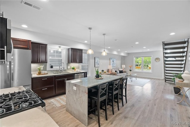 1117 N 31st St, Richmond, VA 23223 - kitchen featuring open floor plan, light wood-style flooring, a kitchen island, dark brown cabinets, and recessed lighting