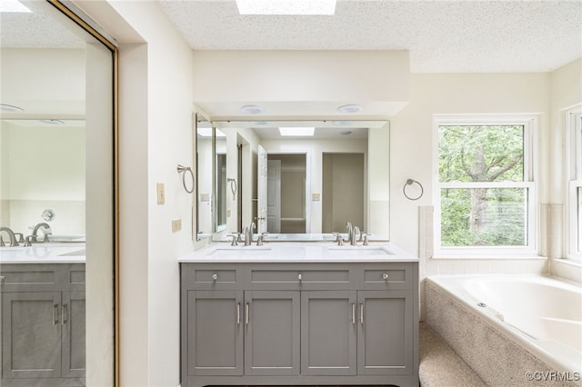 9645 Benbow Rd, North Chesterfield, VA 23235 - full bathroom featuring double vanity, a garden tub, a skylight, and a textured ceiling