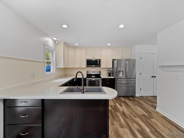 11660 Oakrise Pl, New Kent, VA 23124 - kitchen with stainless steel appliances, a sink, a peninsula, light countertops, and wood finished floors