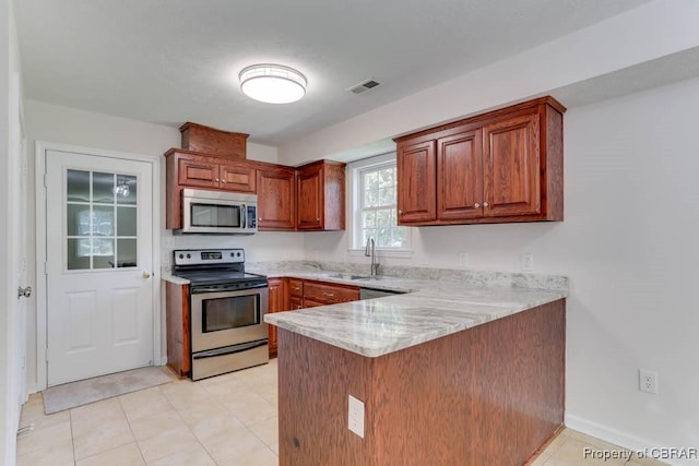 1928 Box St, Hampton, VA 23661 - kitchen featuring appliances with stainless steel finishes, a sink, a peninsula, light stone countertops, and brown cabinets