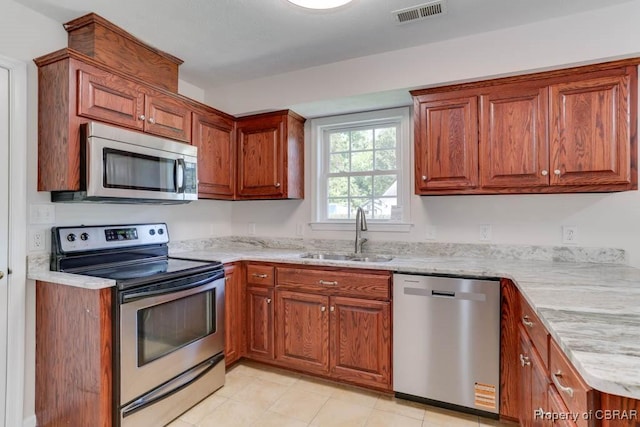 1928 Box St, Hampton, VA 23661 - kitchen with appliances with stainless steel finishes, a sink, brown cabinets, and light stone countertops