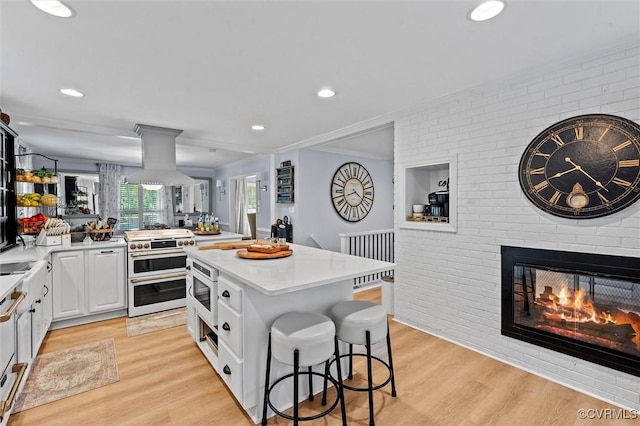905 Manakin Rd, Midlothian, VA 23113 - kitchen featuring range with two ovens, light wood finished floors, light countertops, a breakfast bar, and brick wall