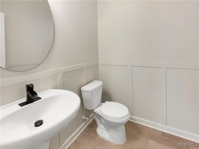 5812 Olas Ct, Richmond, VA 23224 - bathroom featuring a sink, a decorative wall, wood finished floors, toilet, and a wainscoted wall