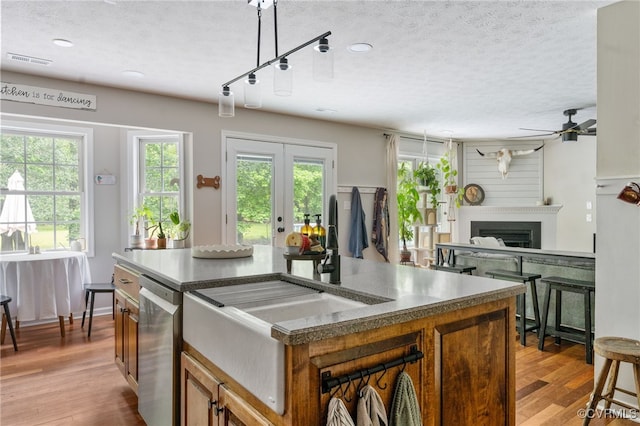 160 Woodland Trl, West Point, VA 23181 - kitchen with ceiling fan, a textured ceiling, brown cabinetry, light wood-type flooring, and a fireplace