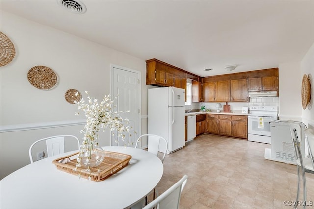 3307 Carlisle Ave, Hopewell, VA 23860 - kitchen featuring white appliances, under cabinet range hood, light countertops, and brown cabinetry