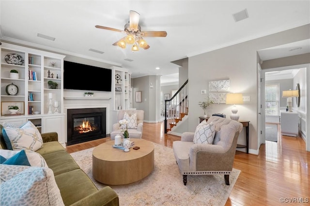 13212 Railey Hill Dr, Midlothian, VA 23114 - living area with stairs, light wood-style floors, ceiling fan, a glass covered fireplace, and ornamental molding
