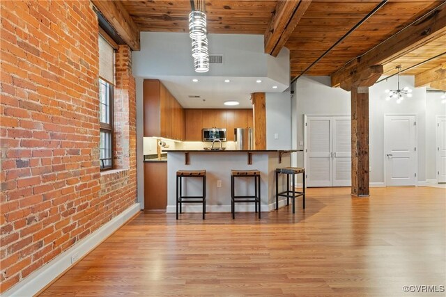 251 Rocketts Way Unit 210, Henrico, VA 23231 - kitchen with appliances with stainless steel finishes, wood ceiling with exposed beams, brick wall, brown cabinetry, and light wood-type flooring