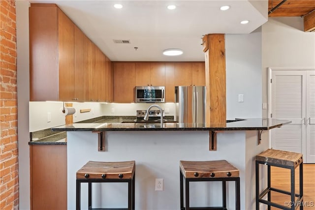 251 Rocketts Way Unit 210, Henrico, VA 23231 - kitchen featuring appliances with stainless steel finishes, dark stone countertops, a peninsula, brick wall, and a breakfast bar