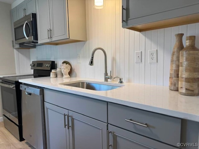 7534 Hollyleaf Ct, Chesterfield, VA 23234 - kitchen with appliances with stainless steel finishes, gray cabinets, a sink, light wood-style flooring, and light stone countertops