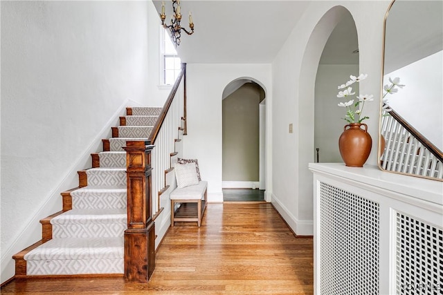 4318 Stuart Ave, Richmond, VA 23221 - stairs with arched walkways, wood finished floors, a chandelier, and baseboards