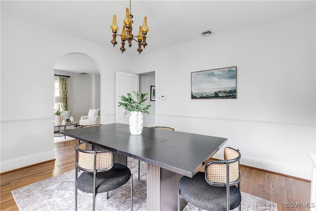 4318 Stuart Ave, Richmond, VA 23221 - dining room with arched walkways, a chandelier, baseboards, and wood finished floors