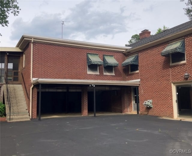 726 S Broad St, Kenbridge, VA 23944 - view of property exterior with asphalt driveway, a garage, brick siding, and a chimney