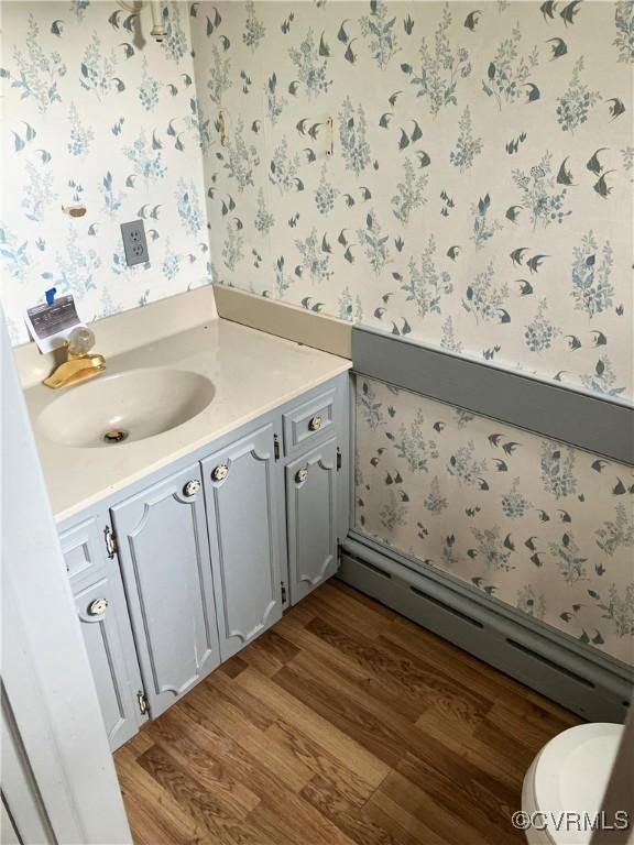 726 S Broad St, Kenbridge, VA 23944 - bathroom with a baseboard heating unit, wallpapered walls, wood finished floors, vanity, and toilet