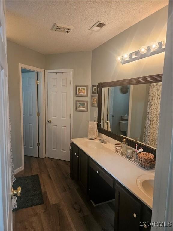6778 Sassafras Dr, Quinton, VA 23141 - bathroom with wood finished floors, double vanity, a textured ceiling, toilet, and a shower with shower curtain