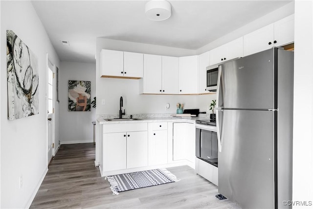 2222 Binford Ln, Richmond, VA 23223 - kitchen with stainless steel appliances, a sink, light countertops, white cabinetry, and light wood-style flooring