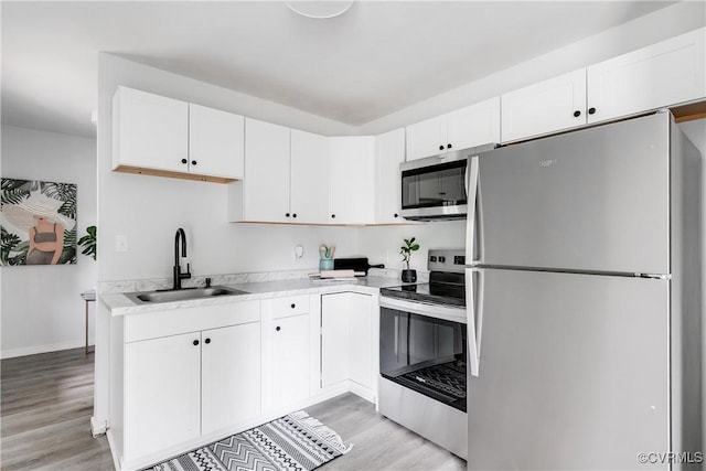 2222 Binford Ln, Richmond, VA 23223 - kitchen with appliances with stainless steel finishes, a sink, light wood-style floors, light countertops, and white cabinets